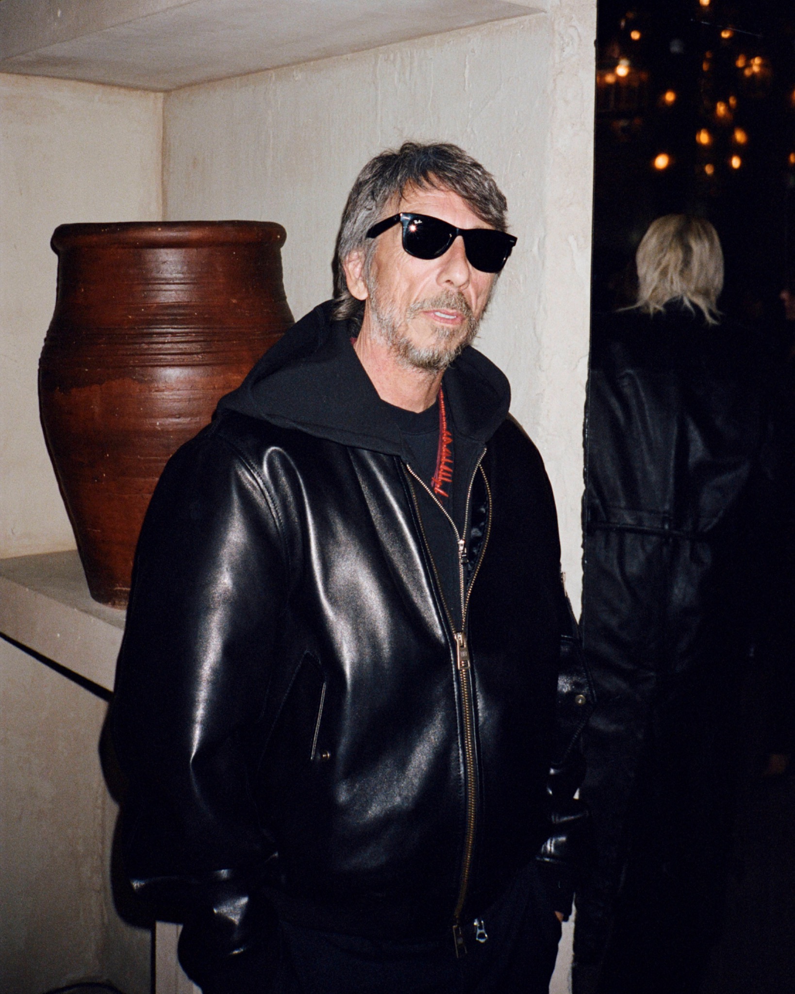 Pierpaolo wearing sunglasses and a black leather jacket, standing indoors beside a large wooden vessel.